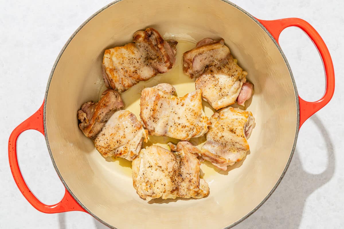 Chicken thighs browning in a large pot.