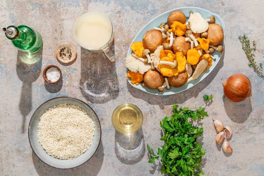 Ingredients for mushroom rice including arborio rice, mixed mushrooms, olive oil, onion, garlic, chicken stock, white wine, fresh thyme, salt, pepper, and parsley.