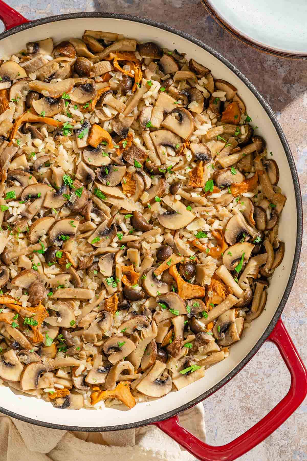 Mushroom rice in a skillet next to a stack of two bowls.
