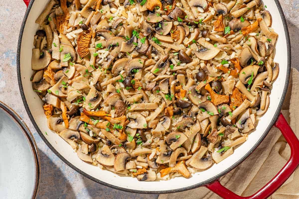 Mushroom rice in a skillet next to a stack of two bowls.