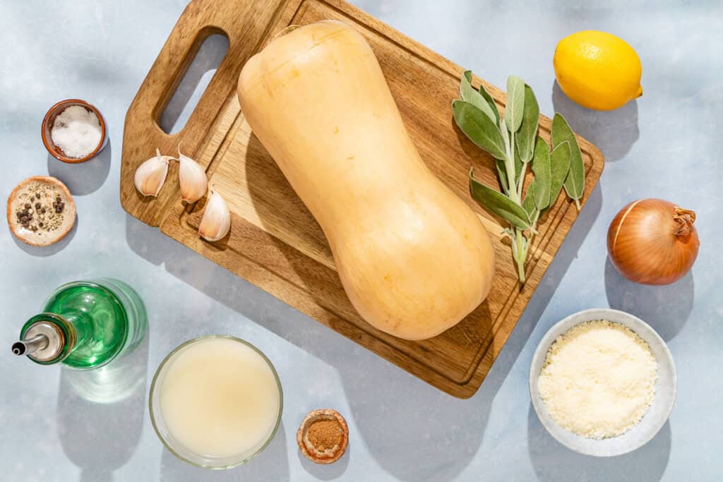 Ingredients for butternut squash pasta sauce including butternut squash, onion, lemon, garlic, olive oil, sage pepper, ground nutmeg, chicken stock and Parmesan cheese.