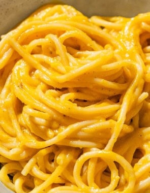 Butternut squash pasta sauce mixed with spaghetti in a bowl.