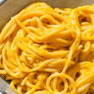 Butternut squash pasta sauce mixed with spaghetti in a bowl.