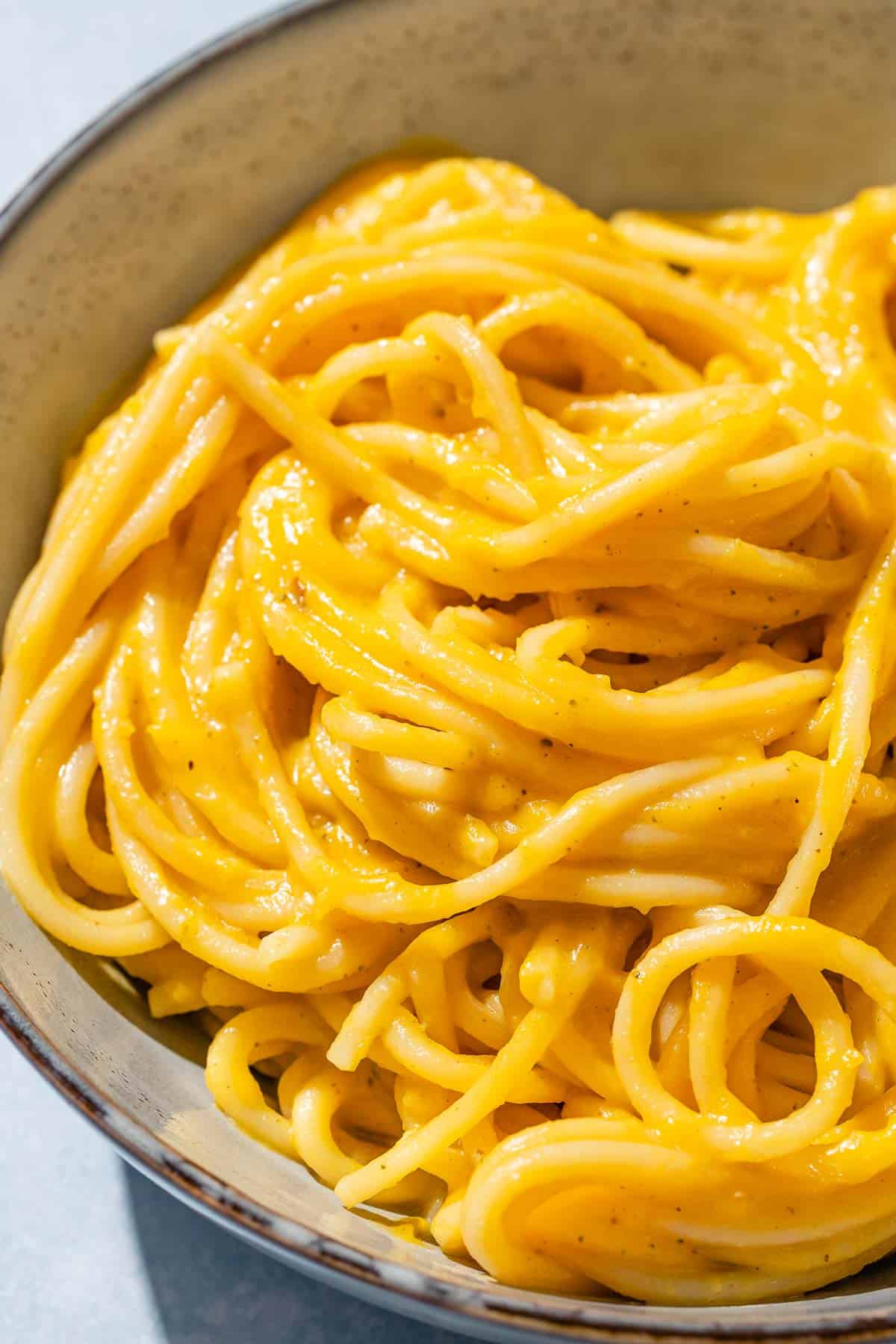 Butternut squash pasta sauce mixed with spaghetti in a bowl.