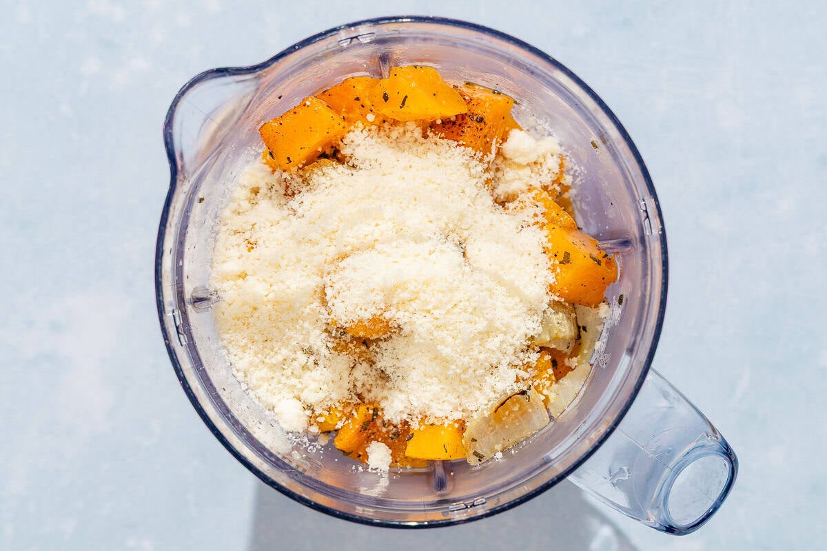 The ingredients for the butternut squash pasta sauce in the pitcher of a blender just before being mixed together.