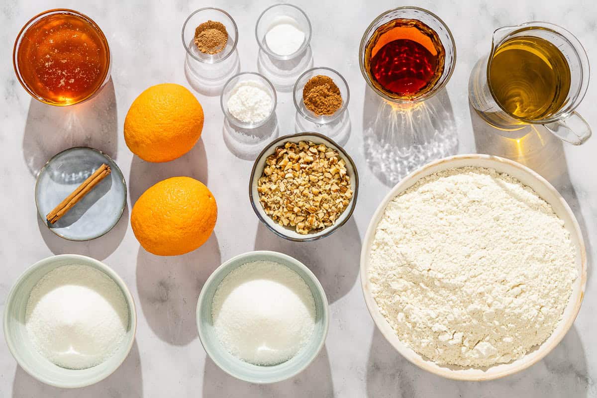 Ingredients all purpose flour, olive oil, brandy, orange, sugar, cinnamon, nutmeg, baking powder, baking soda, walnuts, orange, sugar, a cinnamon stick and honey.