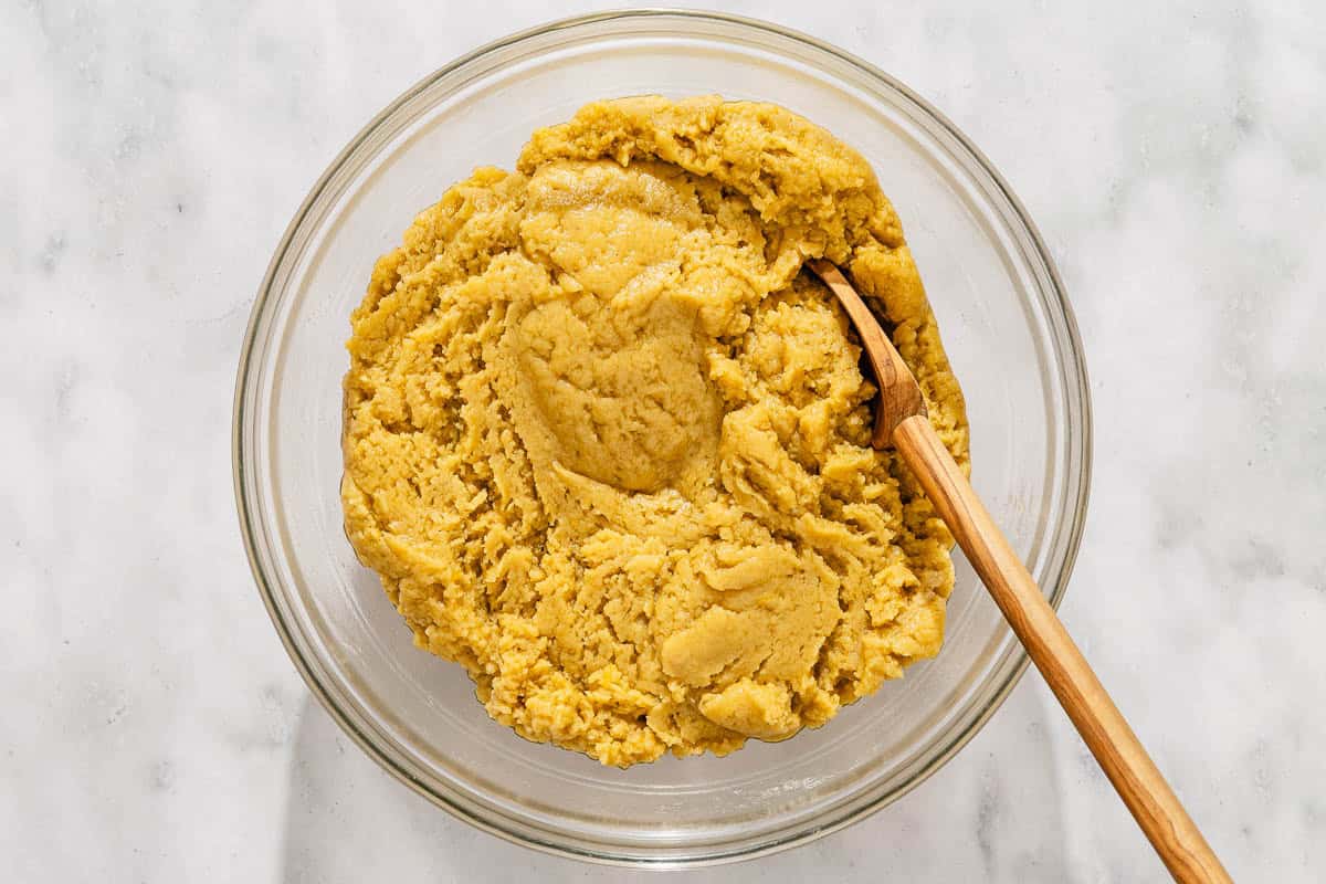 The dough for the melomakarona in a mixing bowl with a wooden spoon.