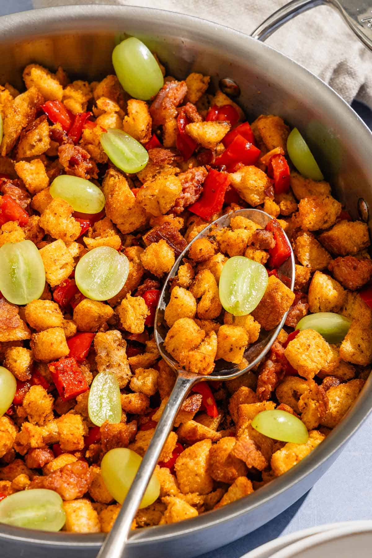 Migas in a tall sided skillet with a serving spoon.