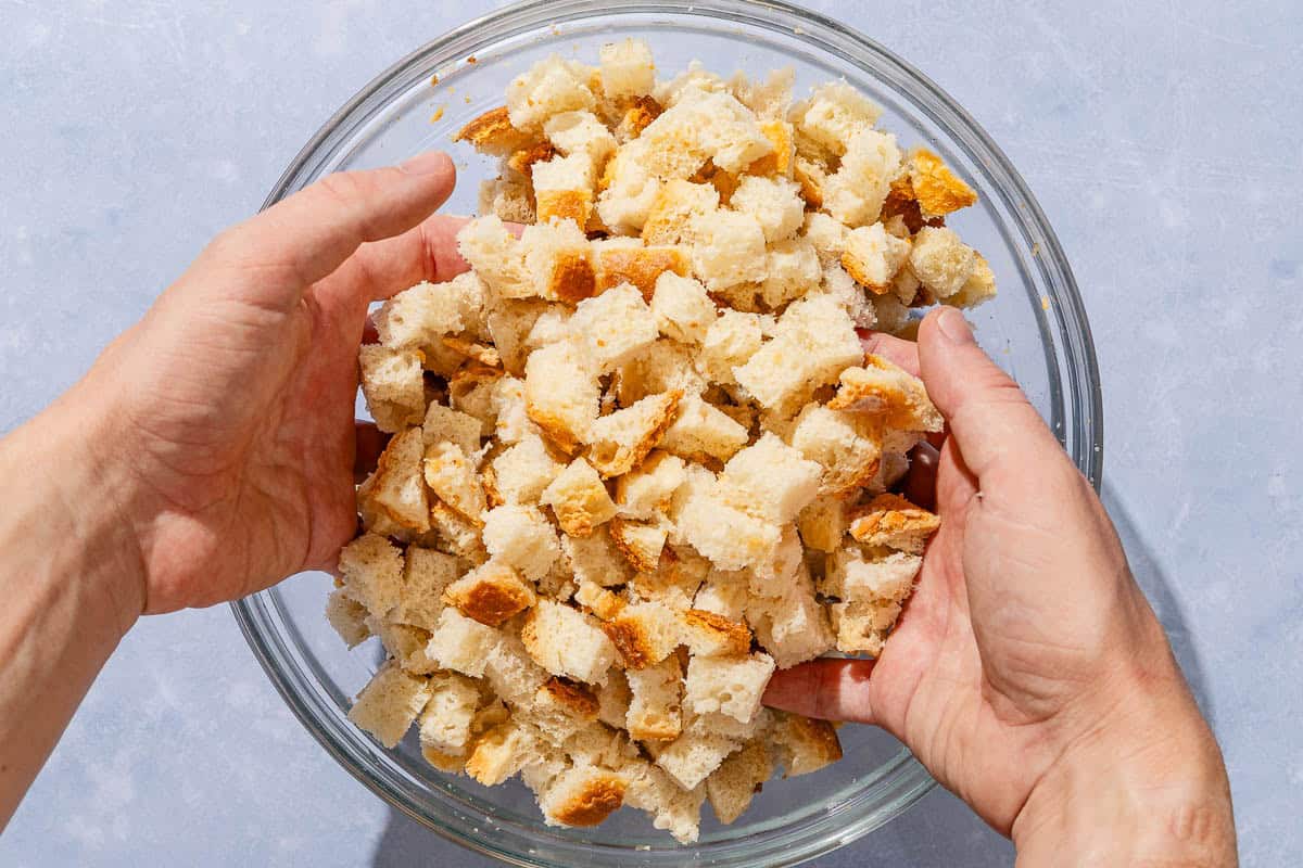 The cubes of crusty bread being tossed with a bit of water in a large bowl.