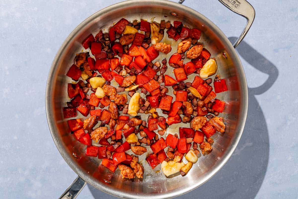 The chorizo, pancetta, and bell pepper for the migas being sautéed in a skillet.