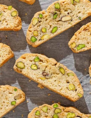 A close up of several slices of pistachio biscotti on a parchment lined sheet pan.