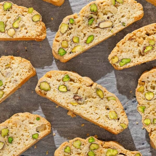 A close up of several slices of pistachio biscotti on a parchment lined sheet pan.