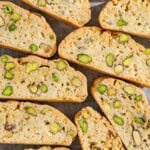 A close up of several slices of pistachio biscotti on a parchment lined sheet pan.