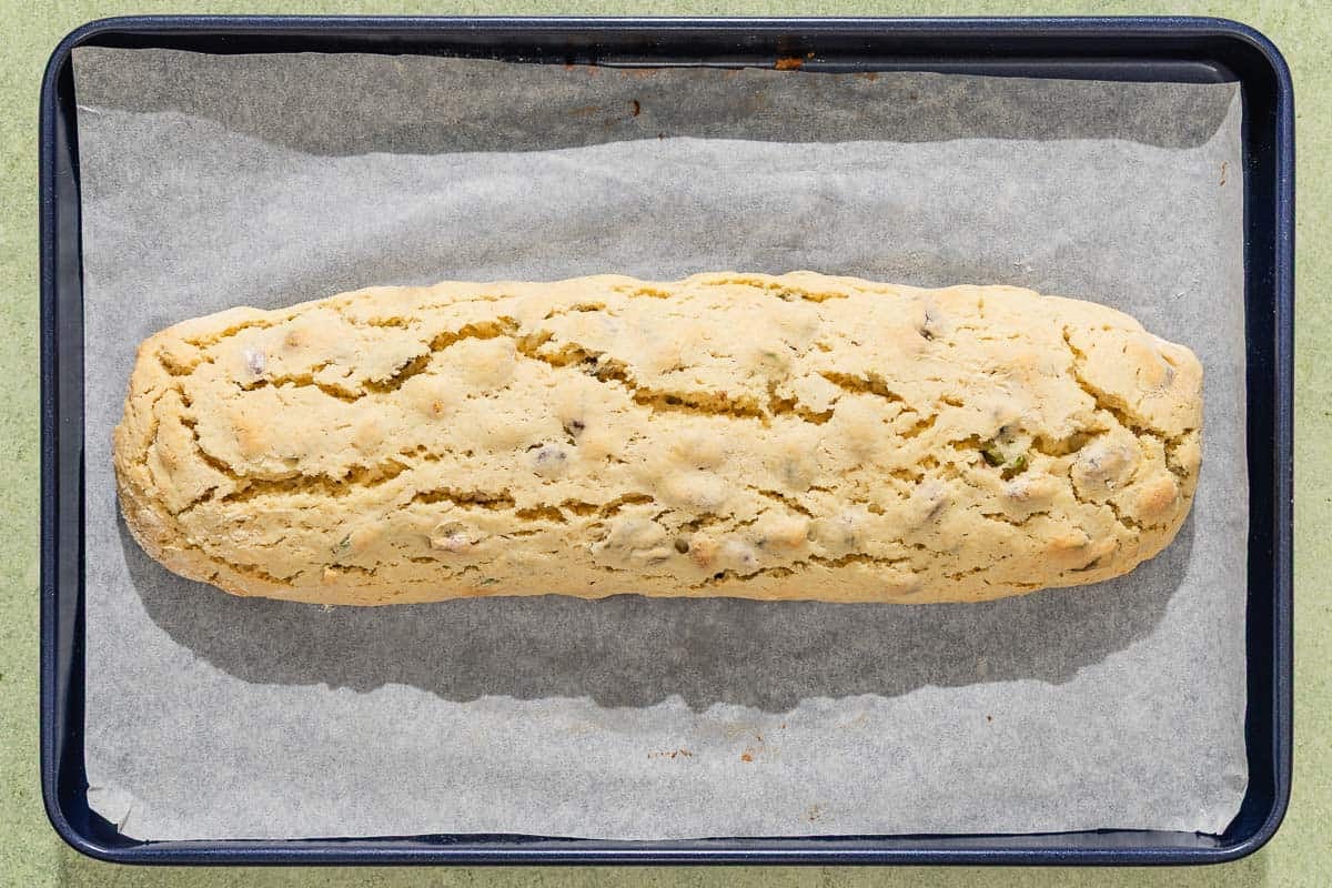 The baked pistachio biscotti on a parchment lined sheet pan before being sliced.