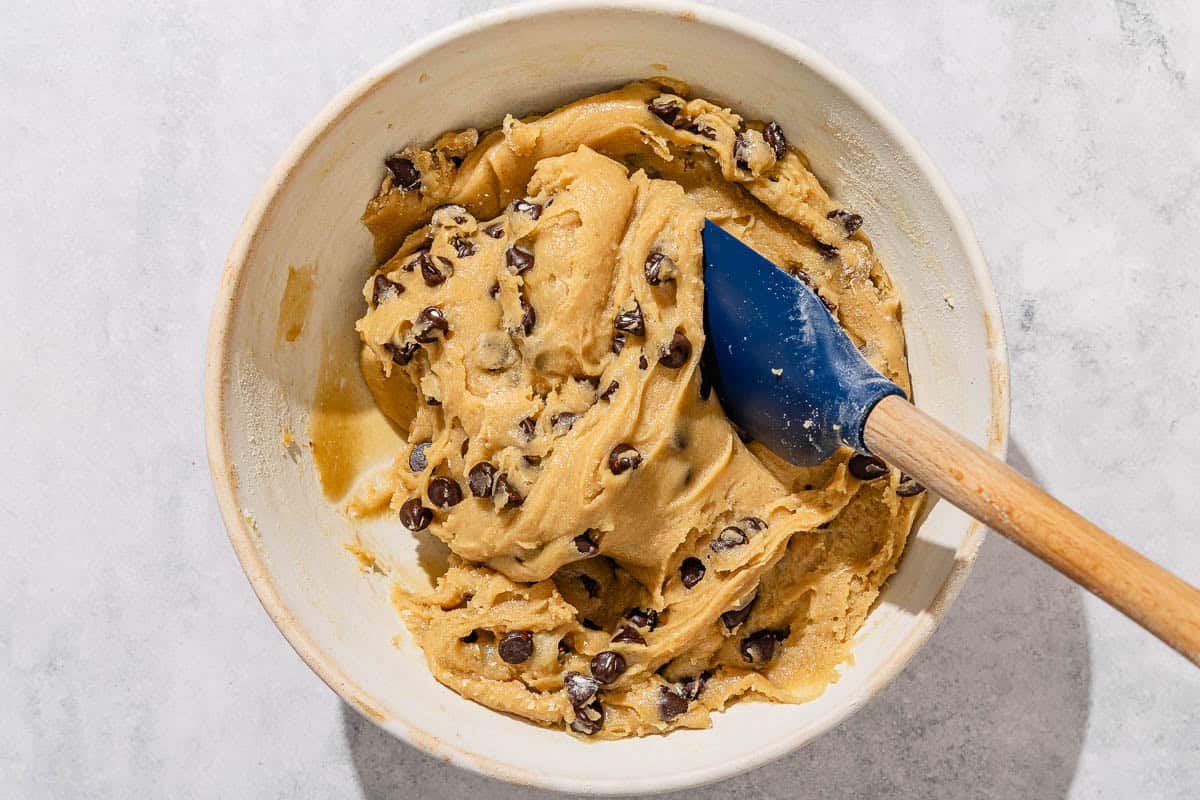 The batter for the tahihi chocolate chip cookies being stirred in a bowl with a spatula.