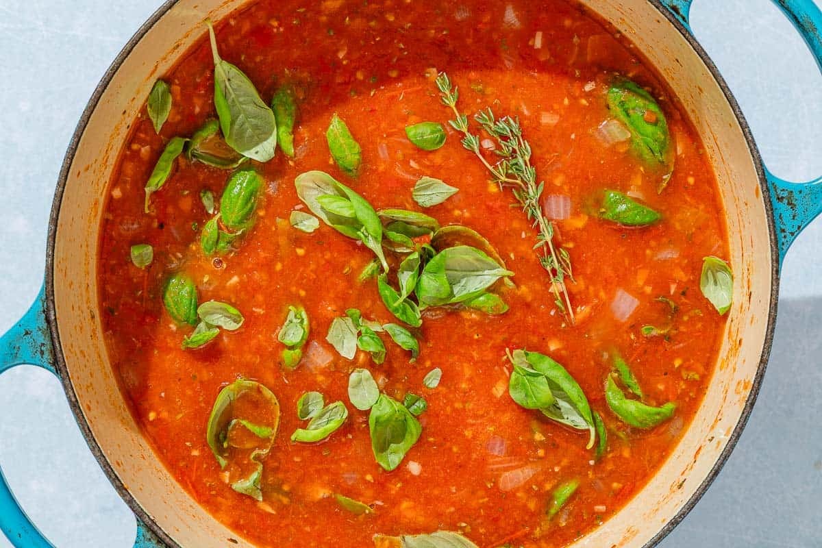 The tomato basil soup in a large pot just after the fresh thyme and basil leaves were added.