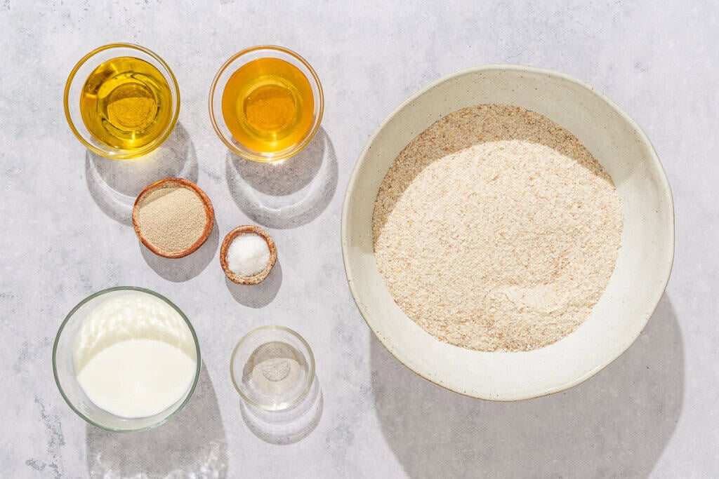 Ingredients for the whole wheat bread recipe including whole wheat flour, water, milk, honey, olive oil, apple cider vinegar, instant yeast, and salt.