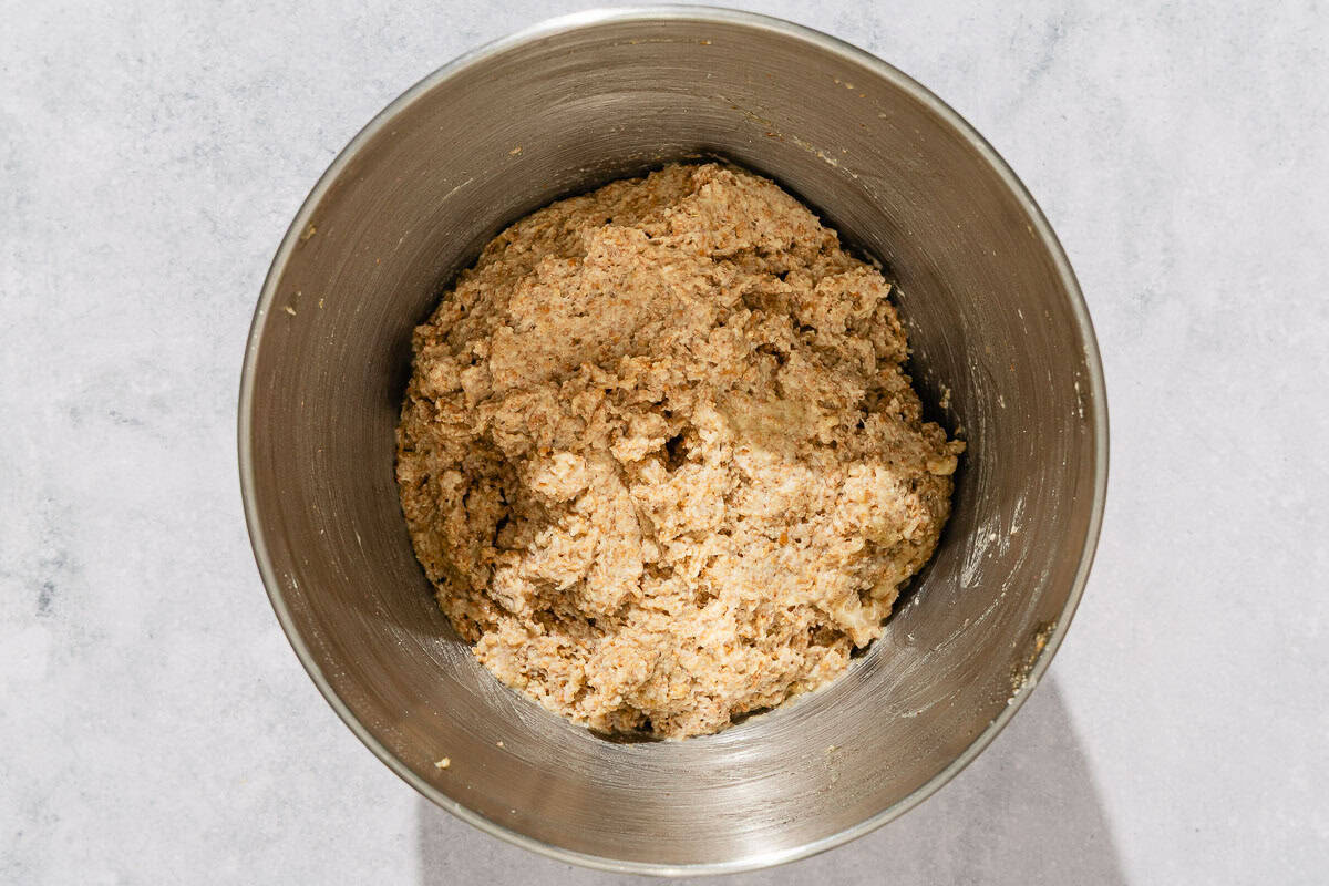 The dough mixture for the whole wheat bread recipe in the bowl of a standing mixer.