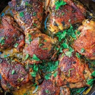Overhead shot of cilantro lime chicken thighs in a cast iron skillet.