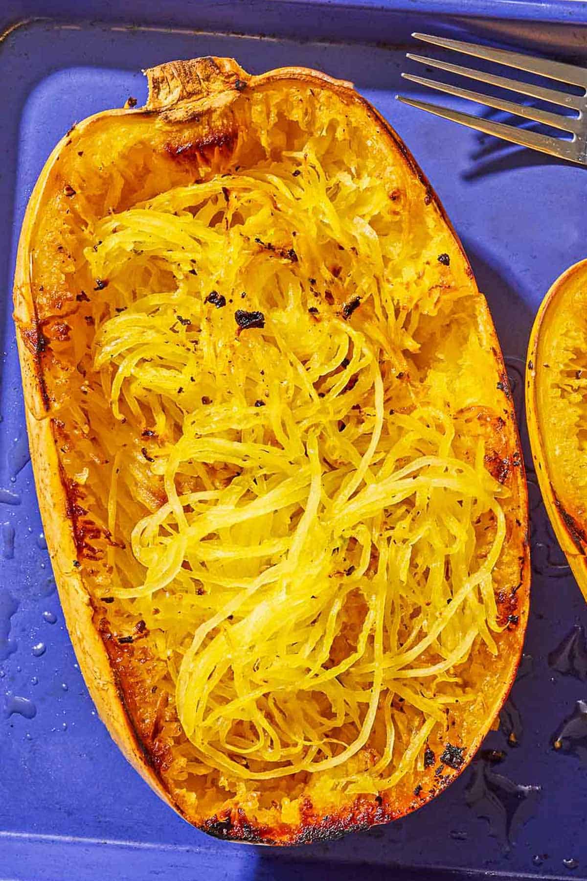 A half of a roasted spaghetti squash baking sheet after its flesh was scraped with a fork.