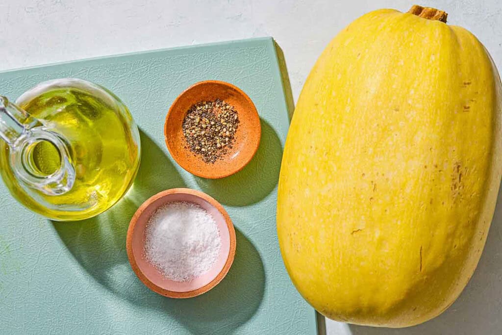Ingredients for how to cook spaghetti squash including a spaghetti squash, salt, pepper and olive oil.