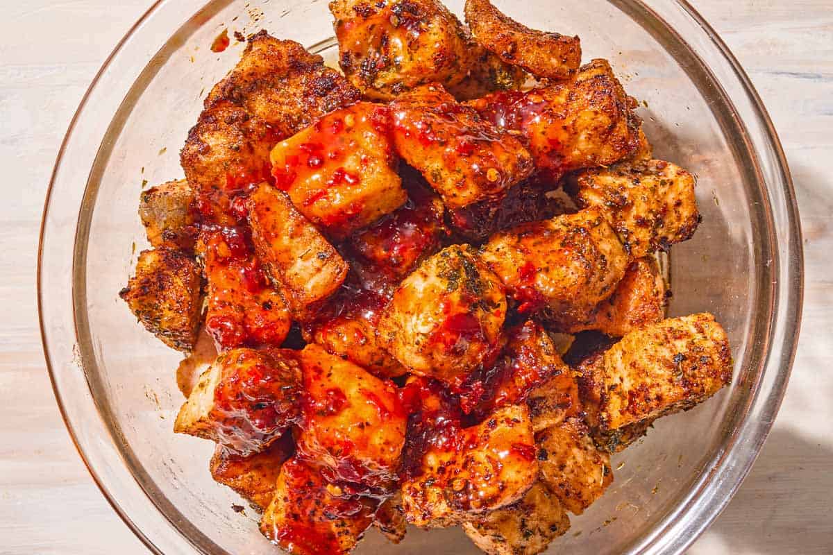 Air fryer salmon bites drizzled with the honey-harissa glaze in a glass bowl.