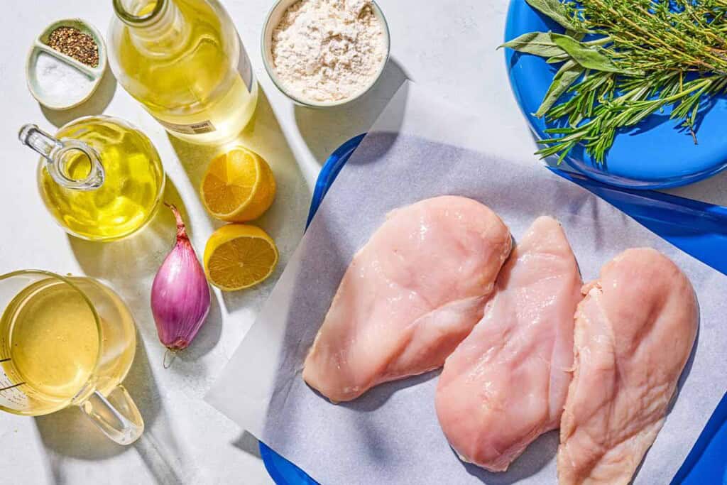 Ingredients for chicken scaloppine including chicken breasts, salt, pepper, flour, olive oil, a shallot, fresh herbs, white wine, chicken stock and lemon.