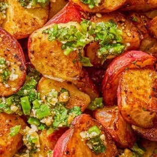 A close up of crispy red skinned potatoes drizzled with walnut cilantro chili sauce.