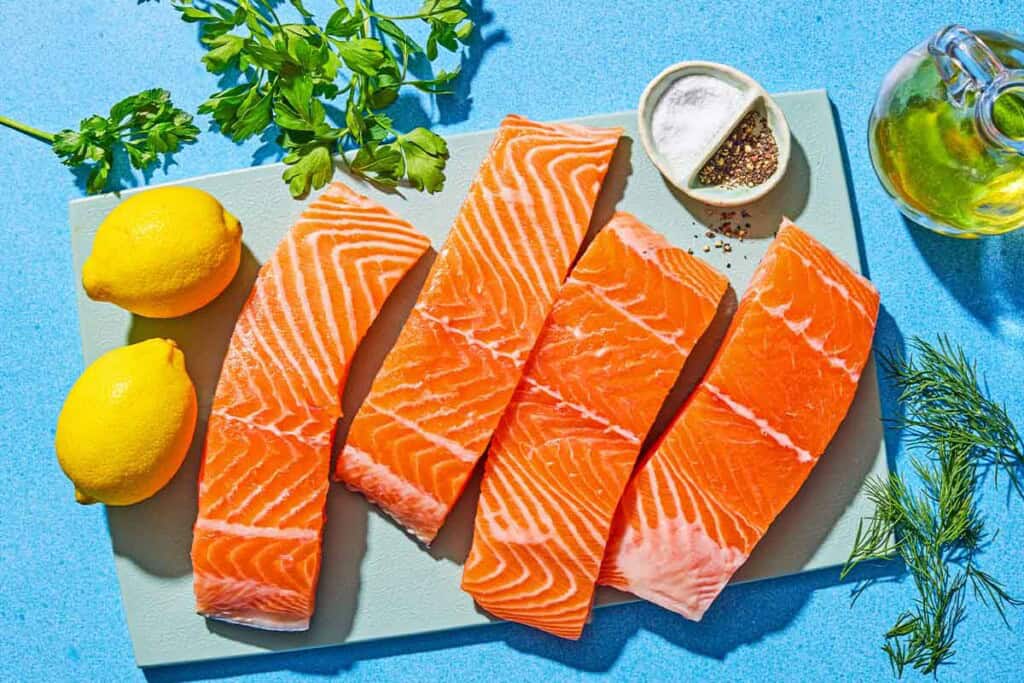 Ingredients for lemon pepper salmon including salmon fillets, olive oil, lemons, olive oil, dill, parsley, salt and pepper.