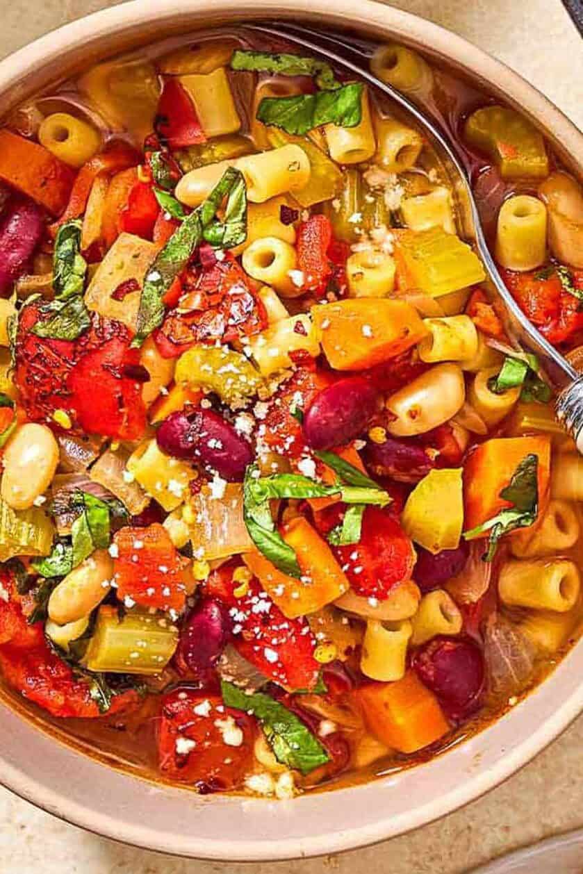 An overhead photo of a bowl of pasta fagioli with a spoon.