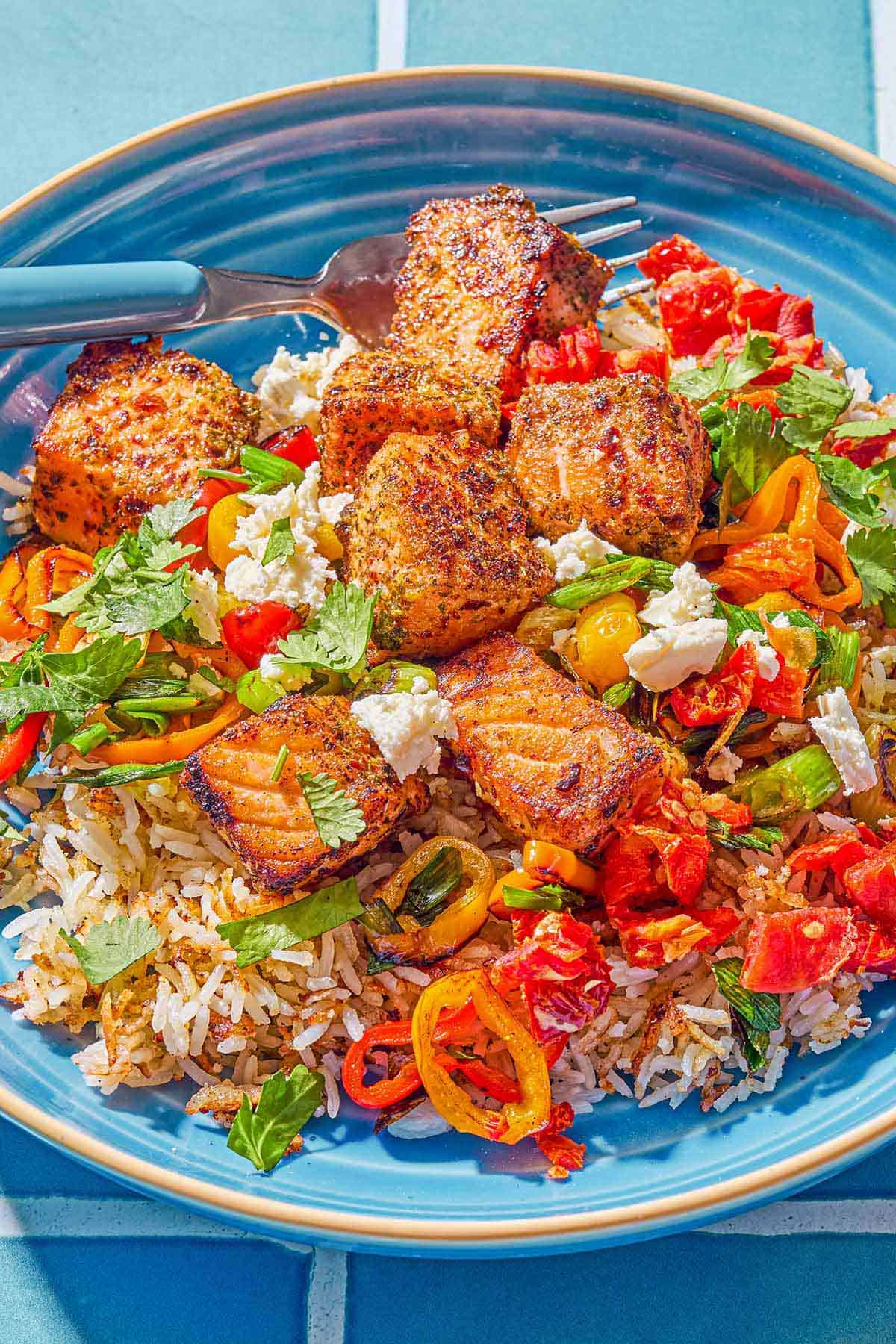 A close up photo of a salmon bowl with a fork.