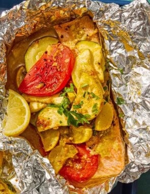 One serving of an open oven baked salmon in foil with vegetables on a sheet pan.