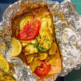 One serving of an open oven baked salmon in foil with vegetables on a sheet pan.