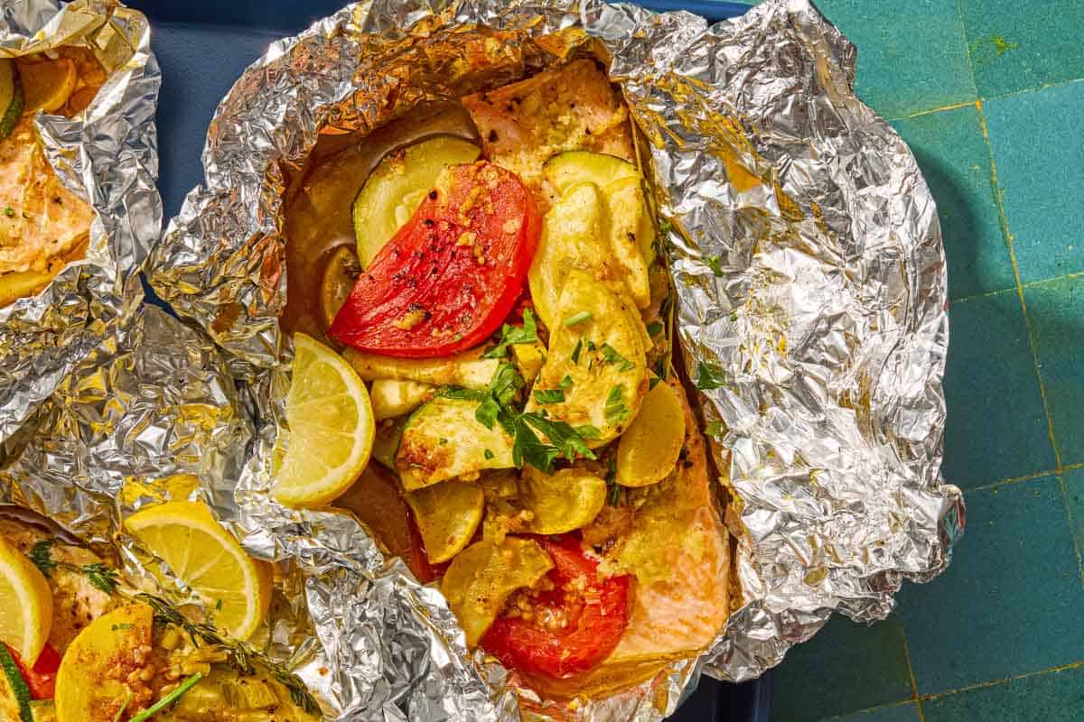 One serving of an open oven baked salmon in foil with vegetables on a sheet pan.