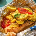 One serving of an open oven baked salmon in foil with vegetables on a plate with a fork. - 15