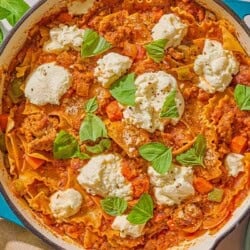 Skillet lasagna in a skillet next sprigs of fresh basil.