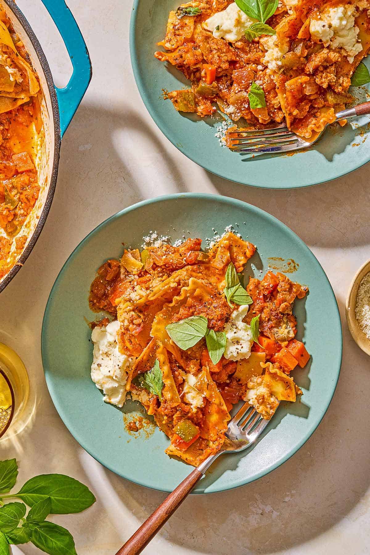 Two servings of skillet lasagna on plates with forks.