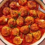 Mozzarella stuffed meatballs in a skillet with a serving spoon.