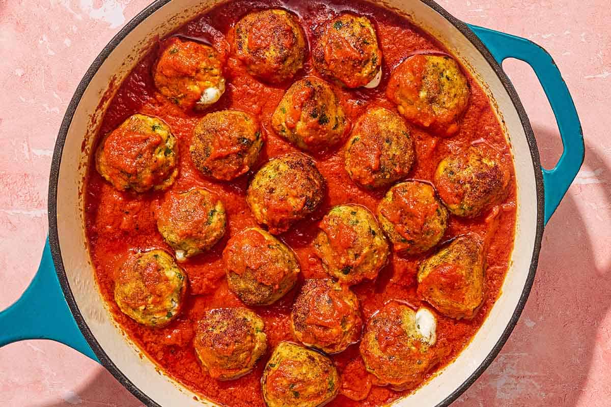 Mozzarella stuffed meatballs in a skillet.