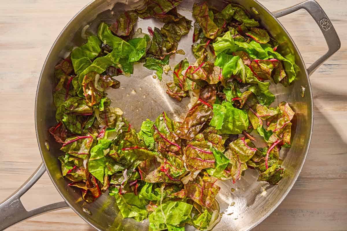 The swiss chard and other vegetables for the pork tenderloin stuffing being sauteed in a skillet.