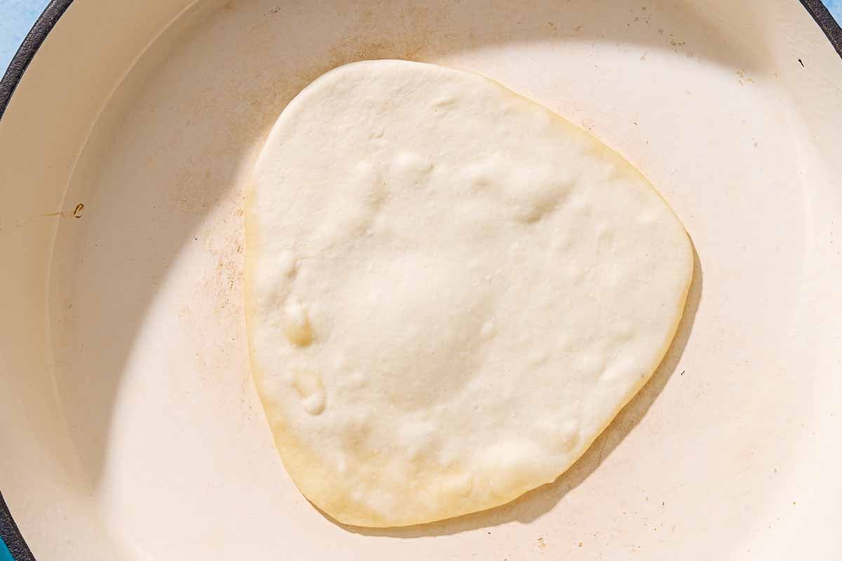 A yogurt flatbread being cooked in a skillet.