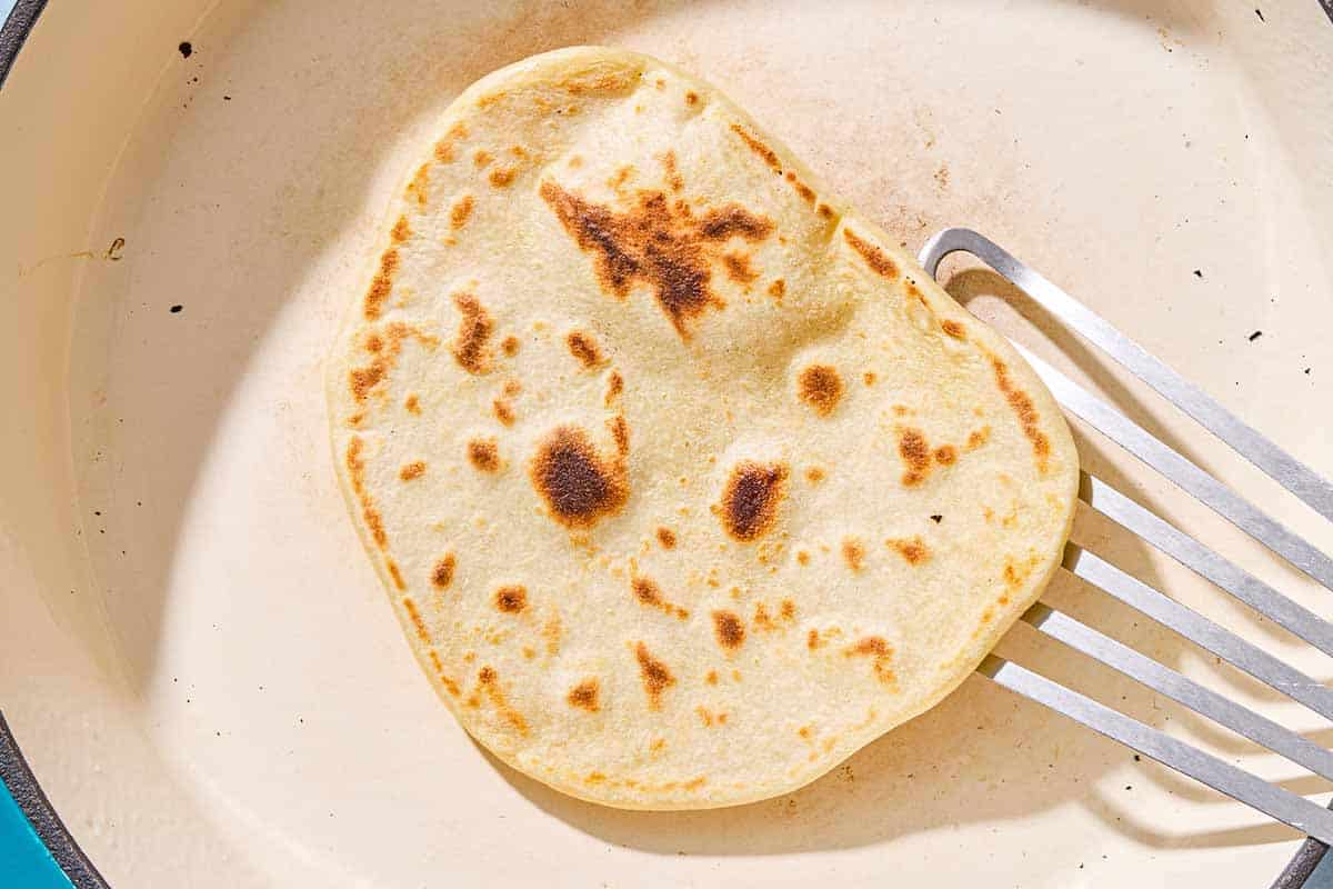 A yogurt flatbread being cooked in a skillet.