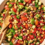 Photo of chickpea salad in a serving bowl with a wooden spoon and fork.