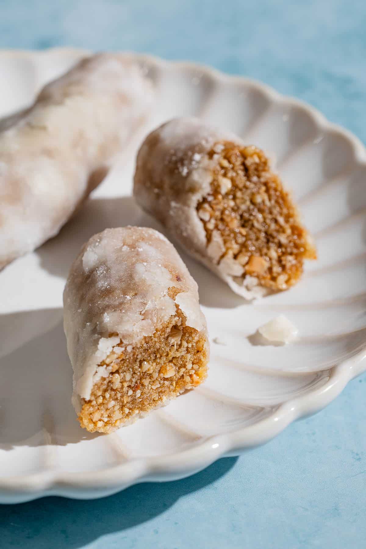 A whole alfajores along with two halves on a plate.