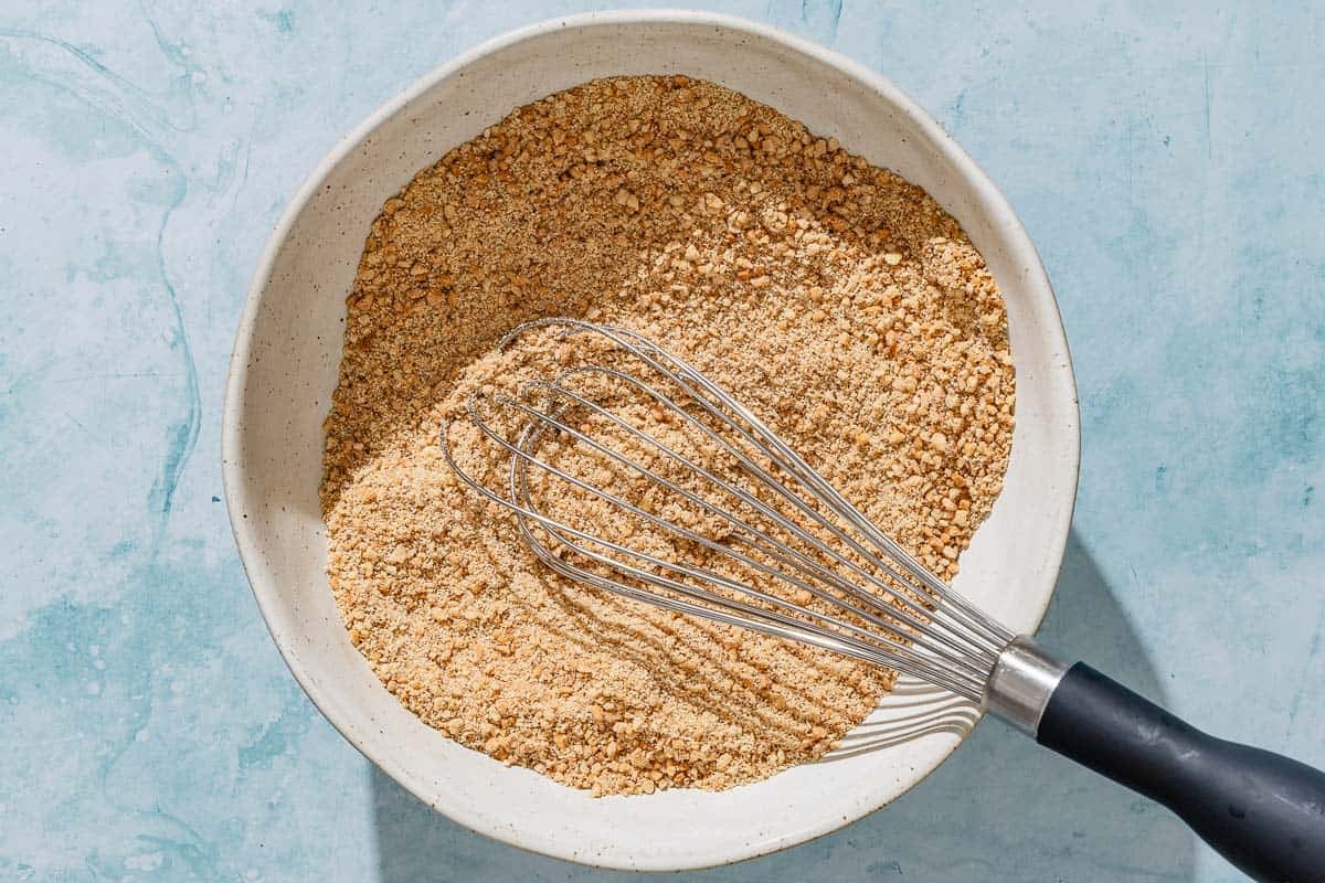 The dry ingredients for the alfajores in a bowl with a whisk.