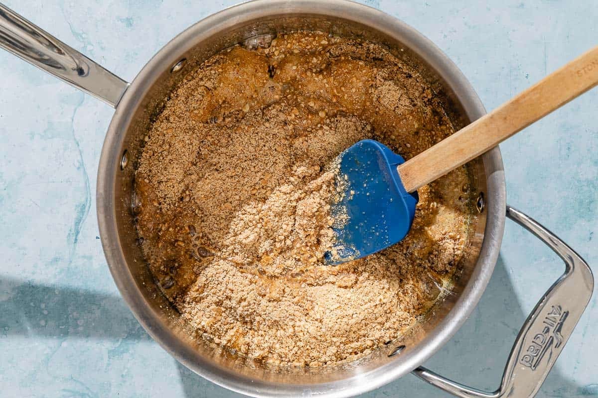 The honey for the alfajores being mixed with the dry ingredients in a saucepan with a spatula.