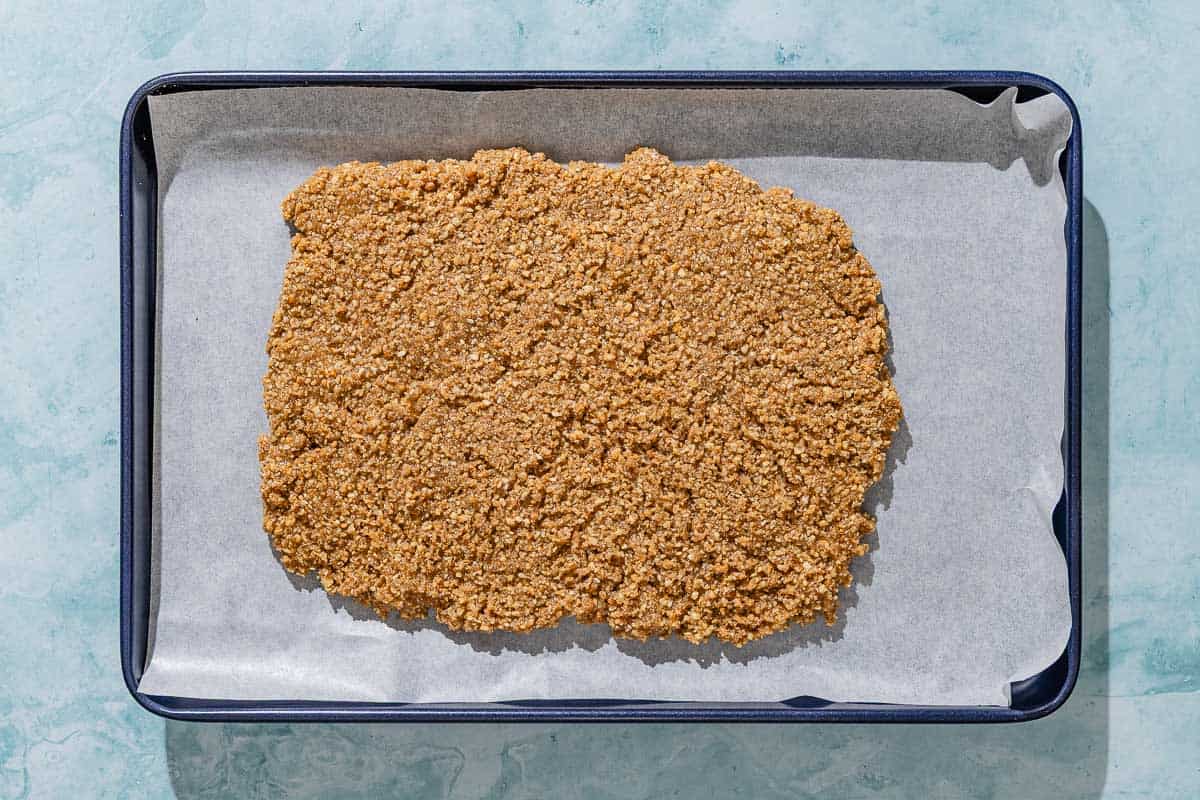 The dough for the alfajores spread out to cool on a parchment lined sheet pan.