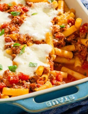 Baked ziti with one serving removed in a baking dish.