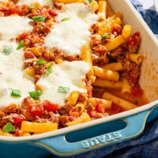 Baked ziti with one serving removed in a baking dish.