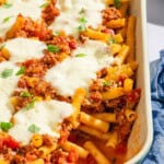 Baked ziti with one serving removed in a baking dish.